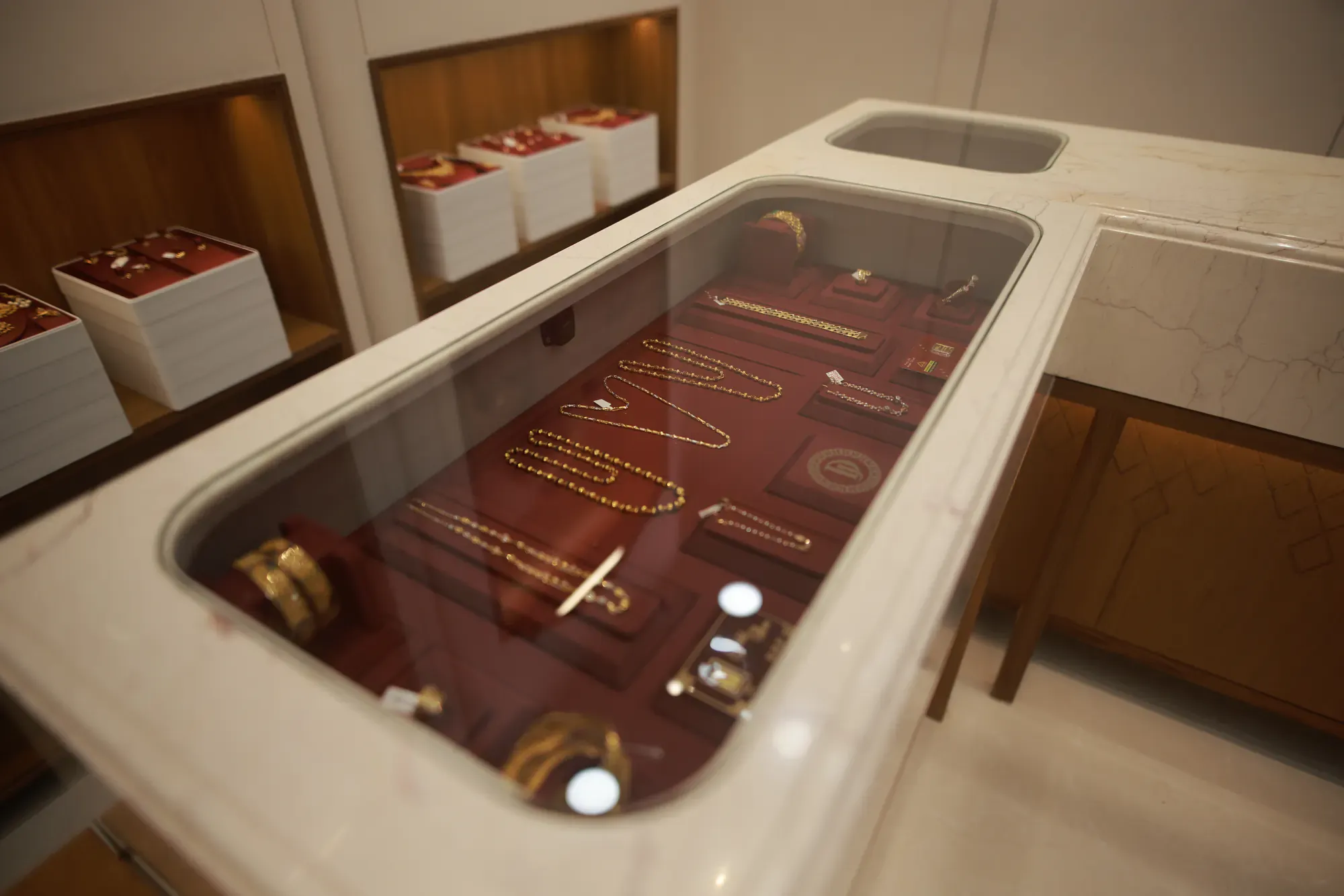 Gold chains and bangles on red velvet in a marble-edged counter