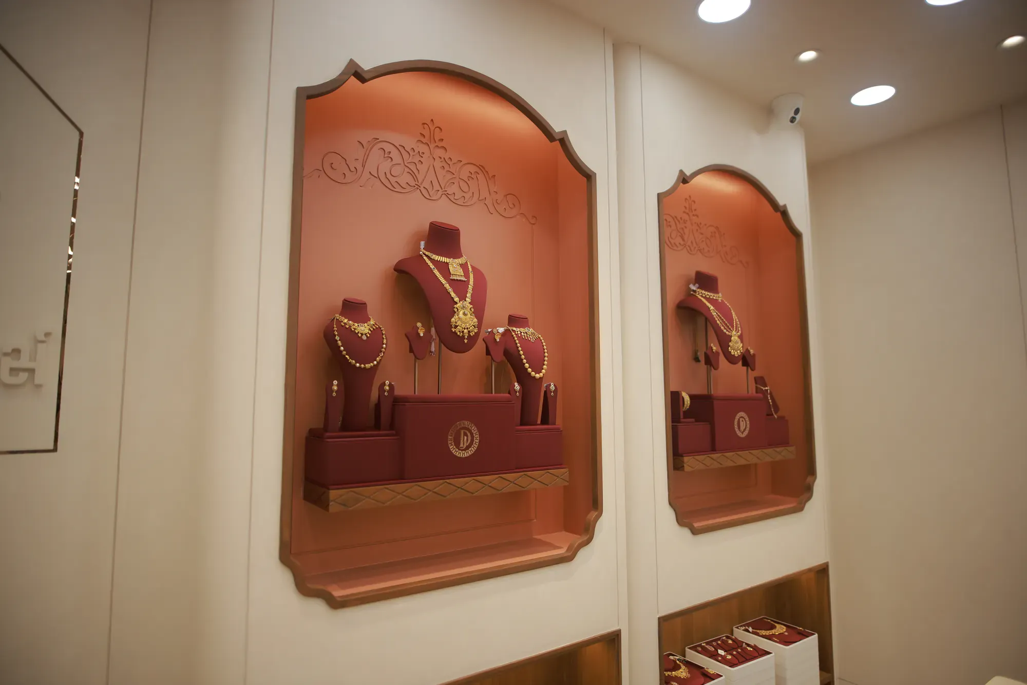 Gold necklaces on velvet busts in a carved arched niche
