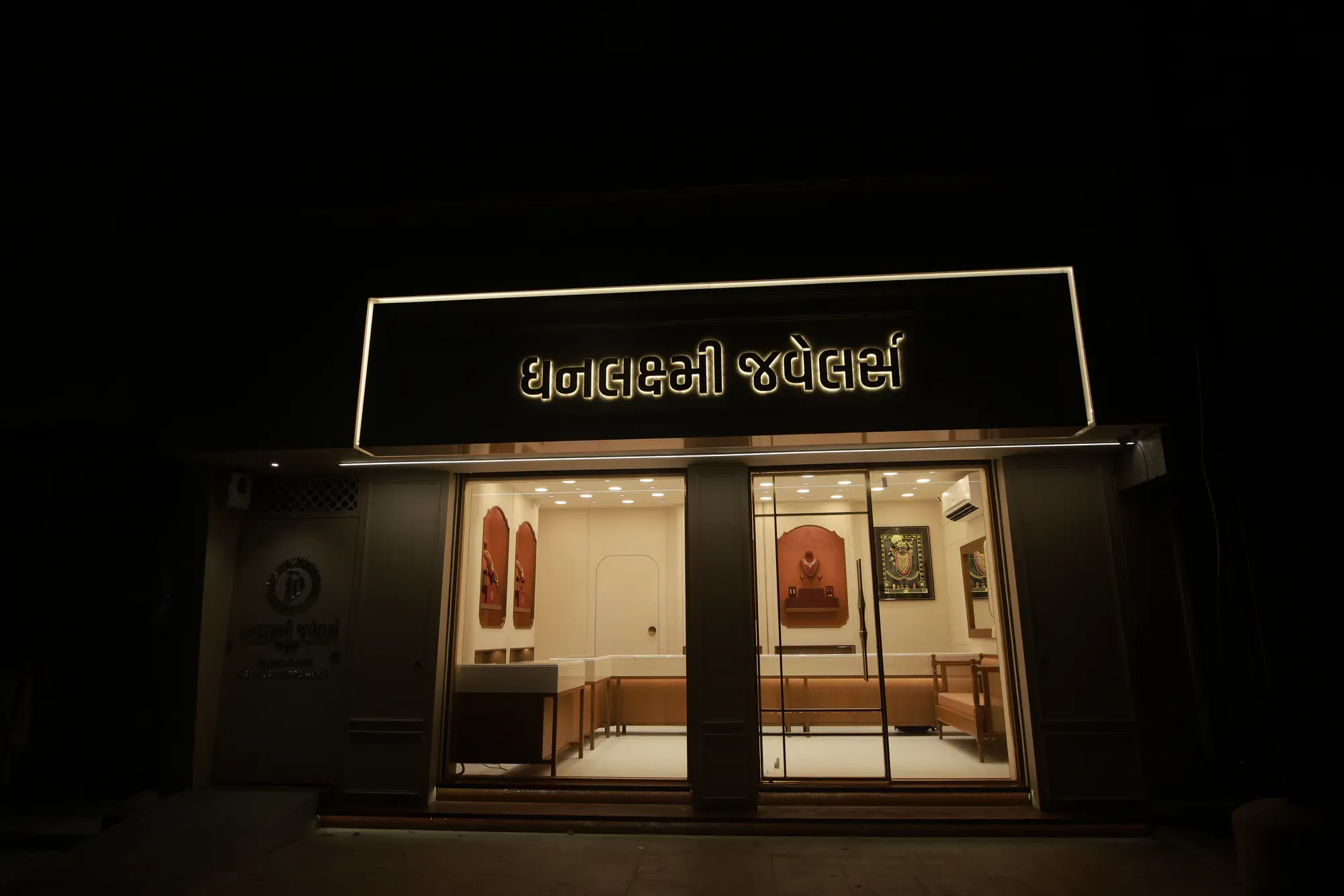 The storefront at night with its gold sign lit